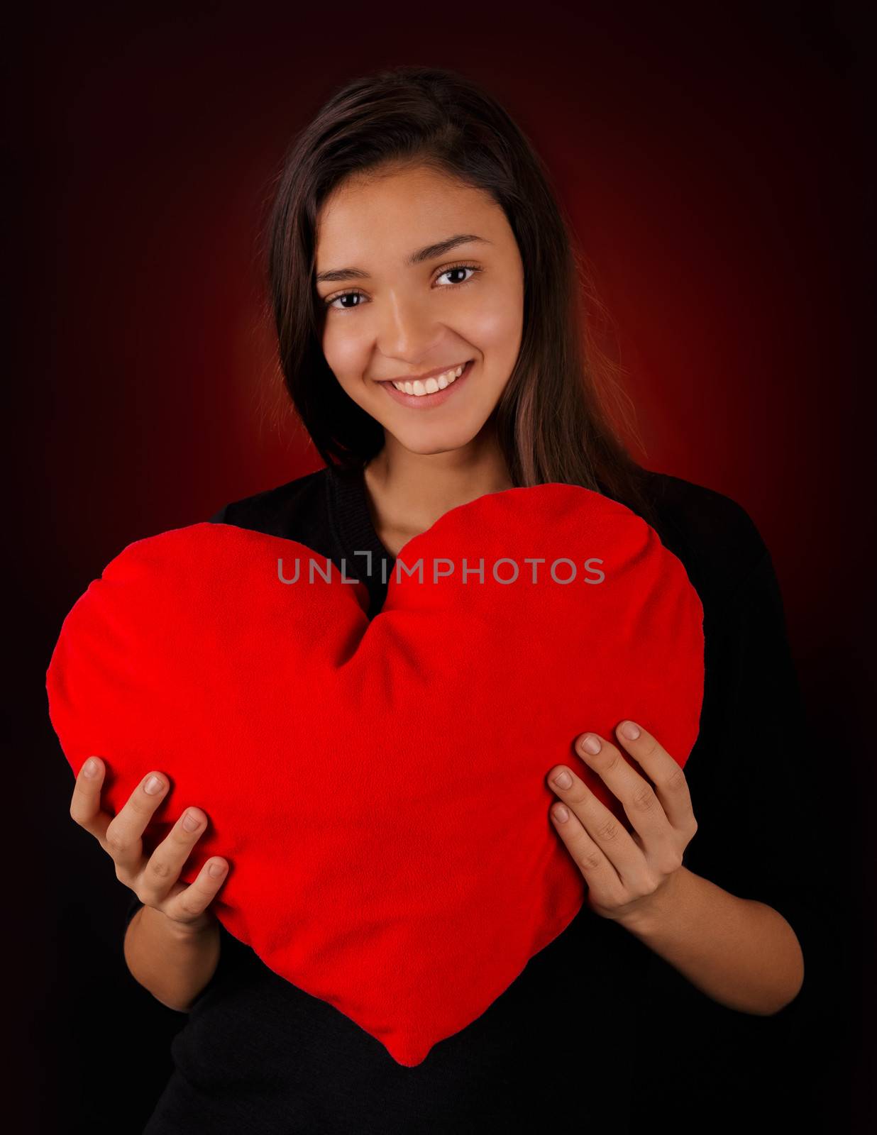 Beautiful girl holding a big plush heart-shaped pillow.