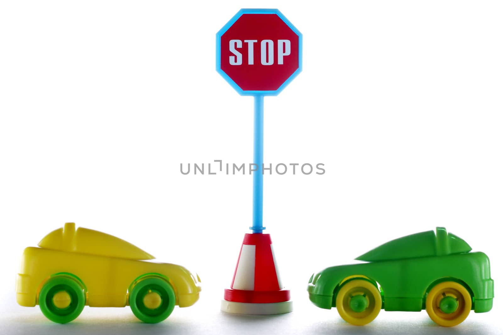 A couple cars behind stop road sign at white background