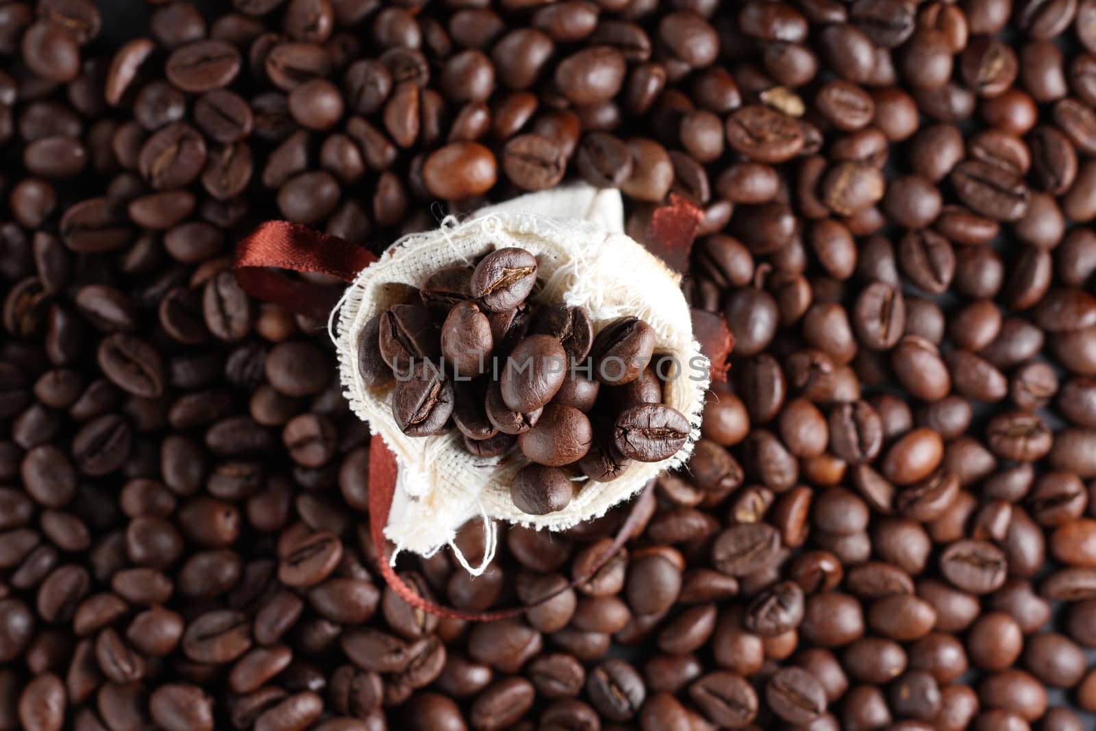 Coffee beans in a sack with a lot of beans around it