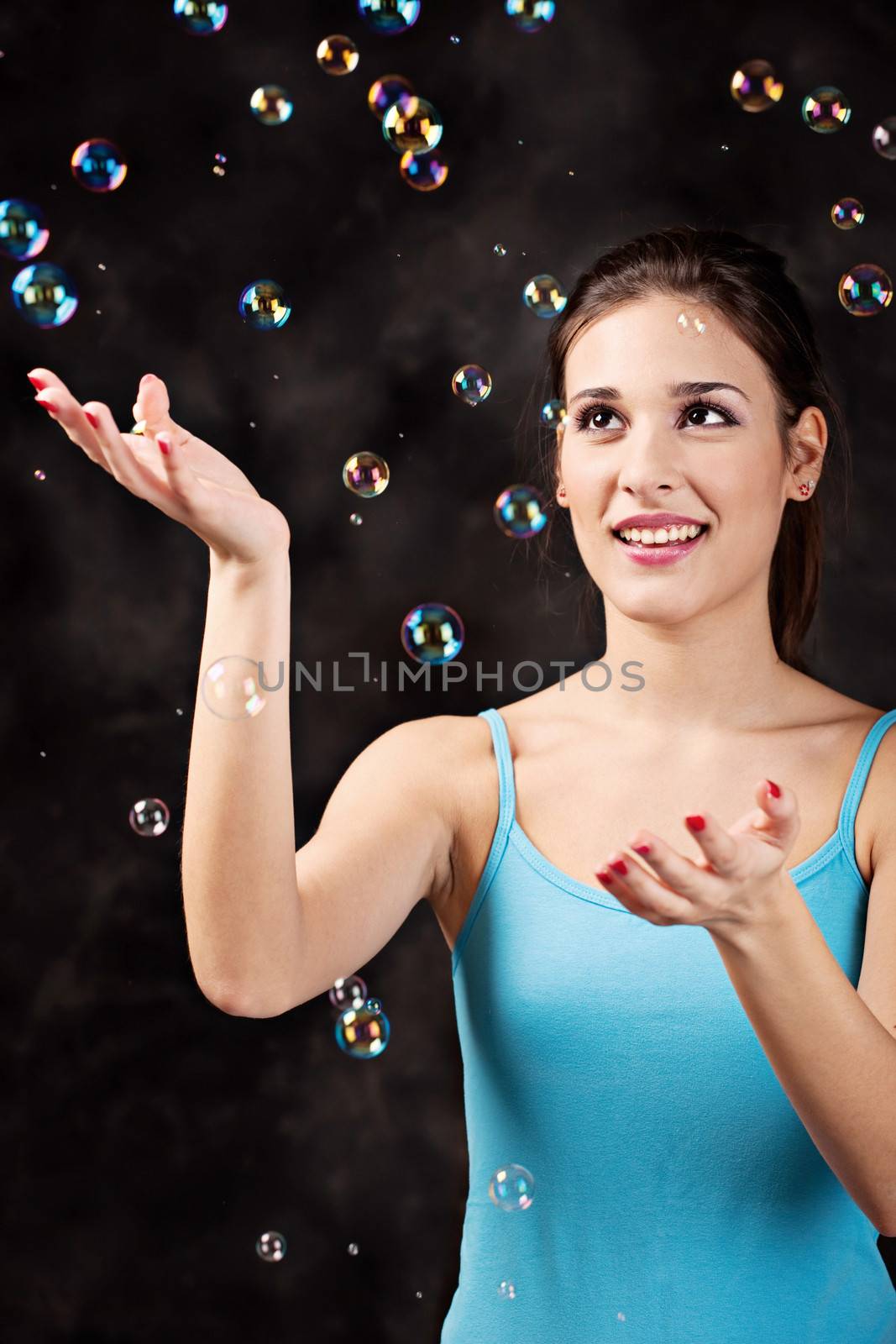 Pretty girl and soap bubbles on the black background