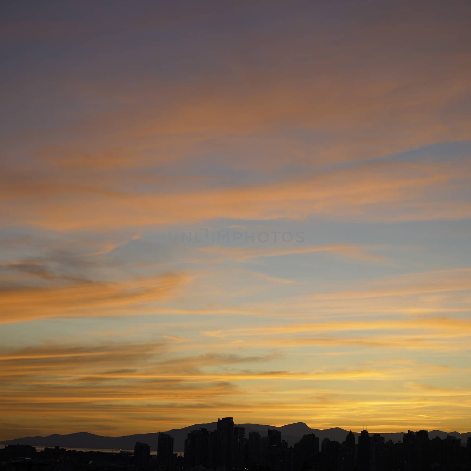 Bright orange sunset over a city, mountains and ocean