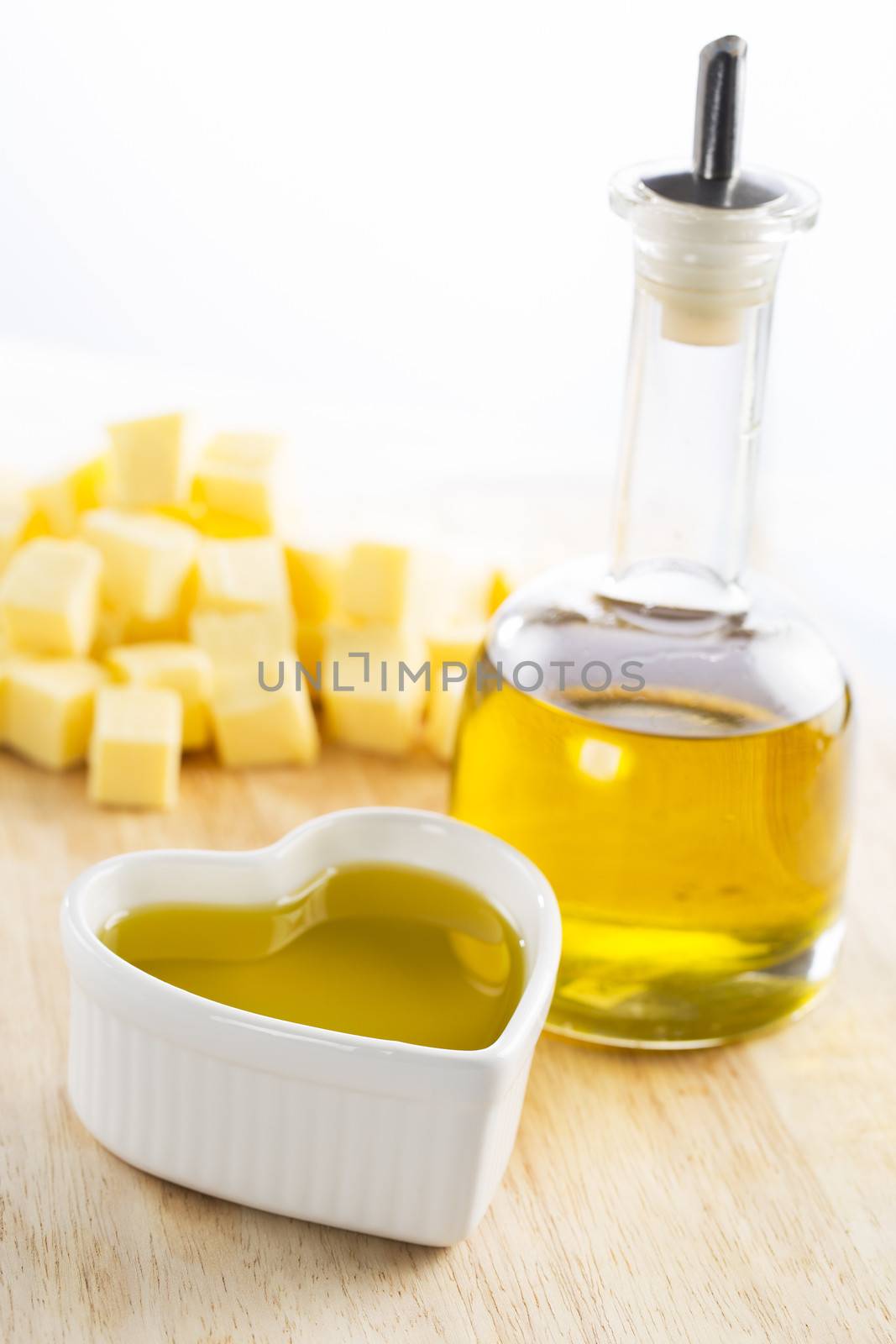 Olive oil in bottle and in a heart with butter in the background