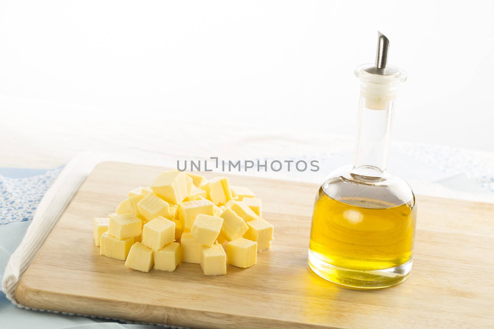 Olive oil in bottle and butter cubes on food preparation surface.
