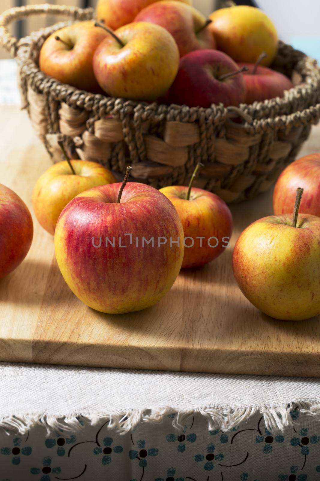 Fresh apples in basket and on board on top of table.