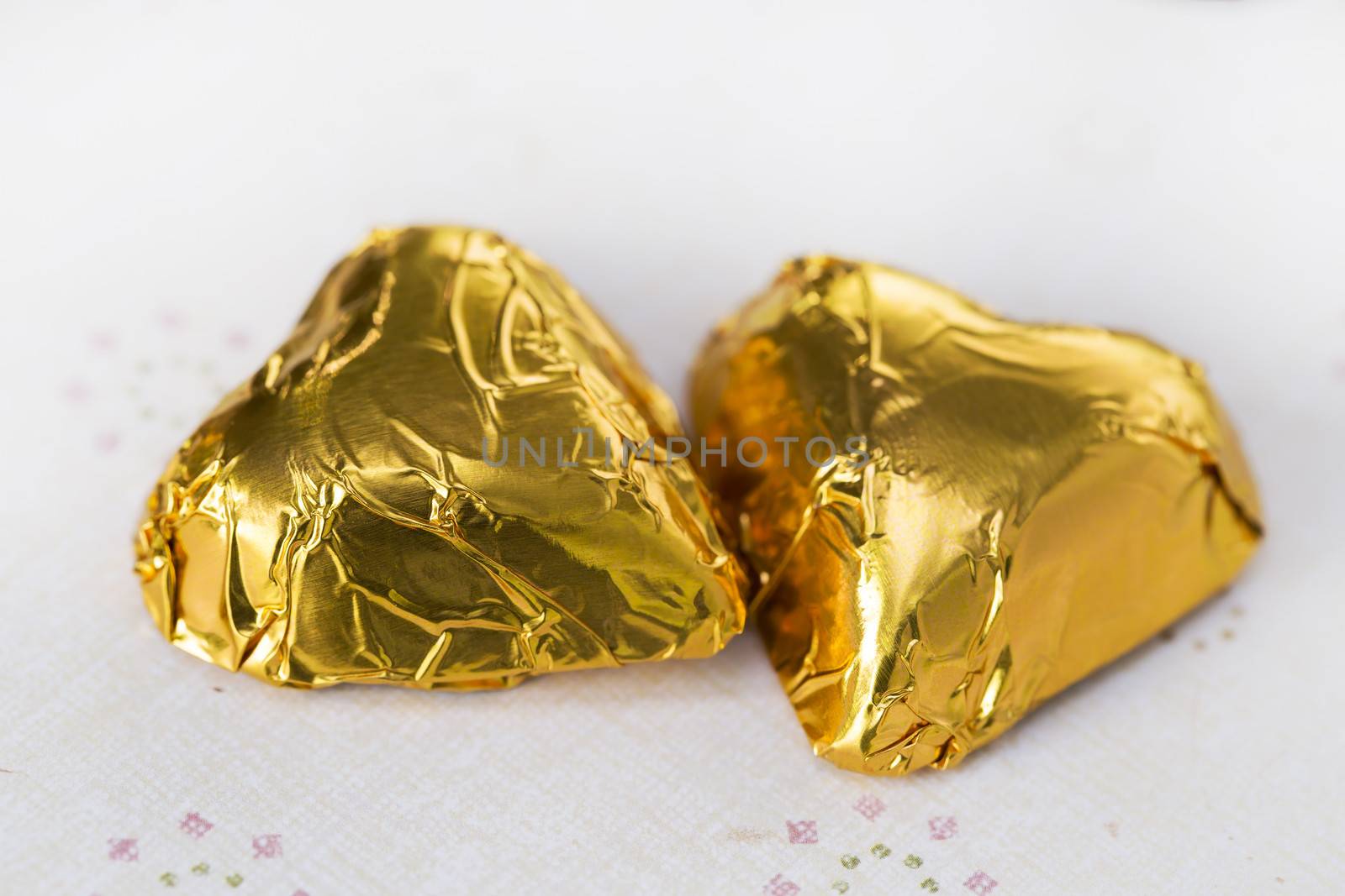 Chocolate candy hearts wrapped in gold foil, close up