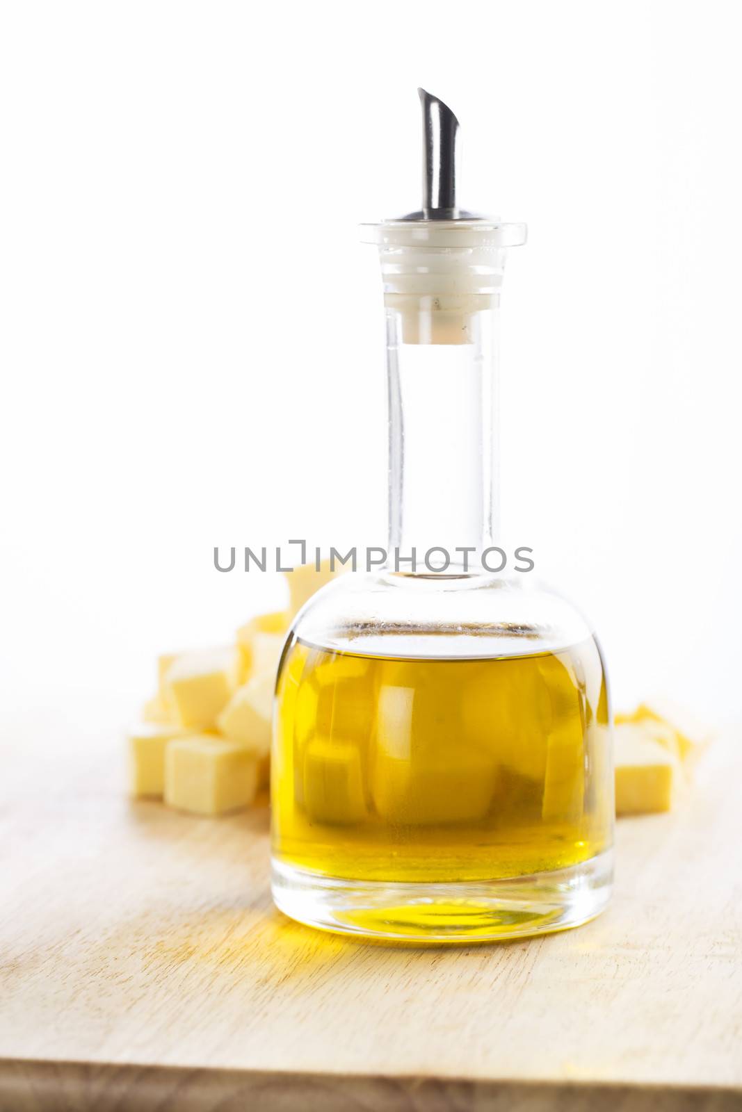 Glass container of olive oil in front of cubes of butter.