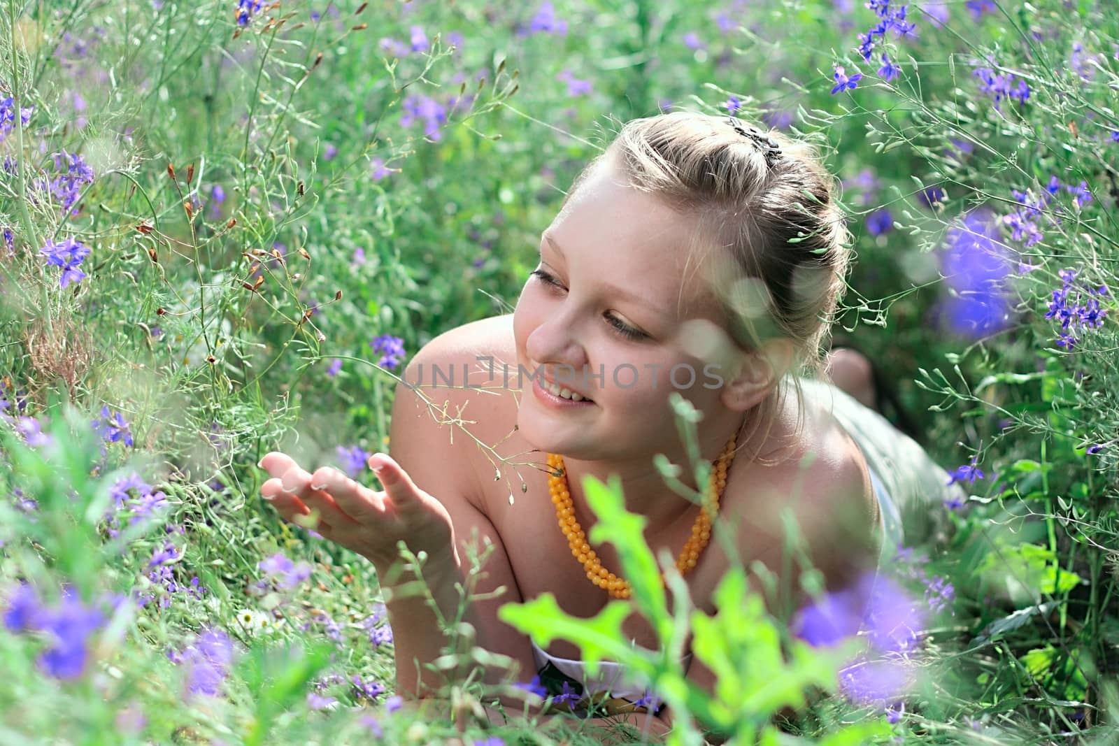 Young girl lying among the flowers on the sunny field