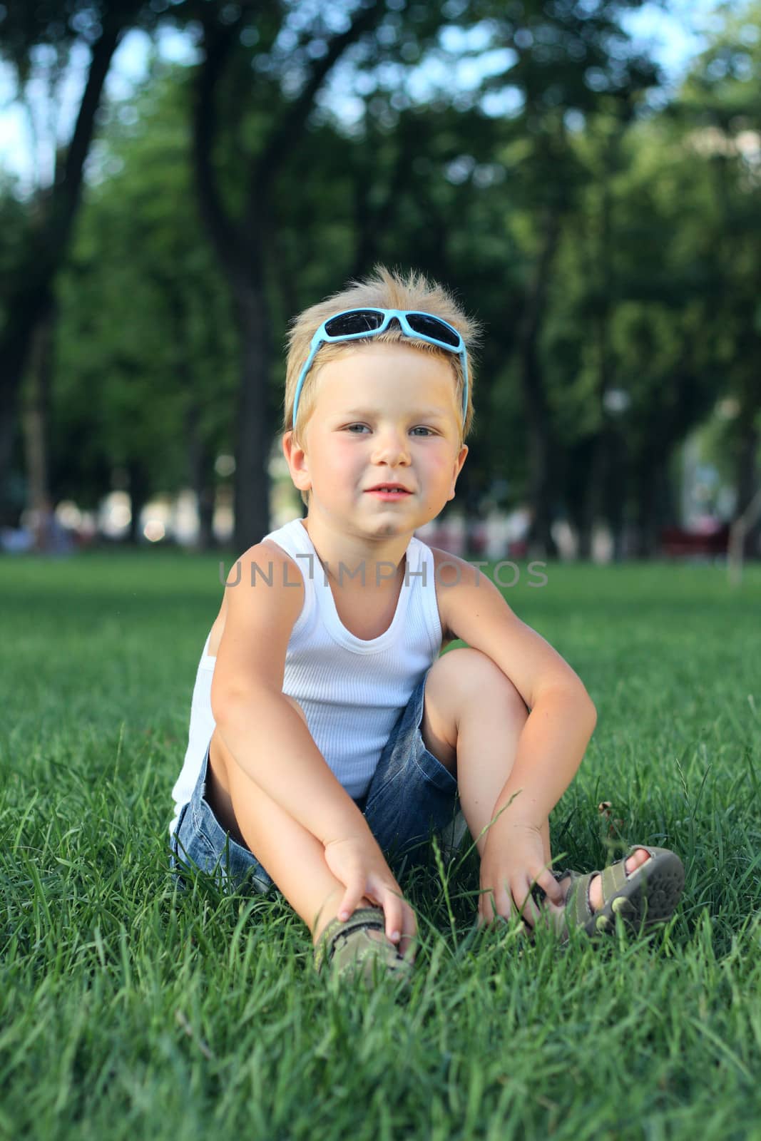 Little boy sitting in the park on a grass
