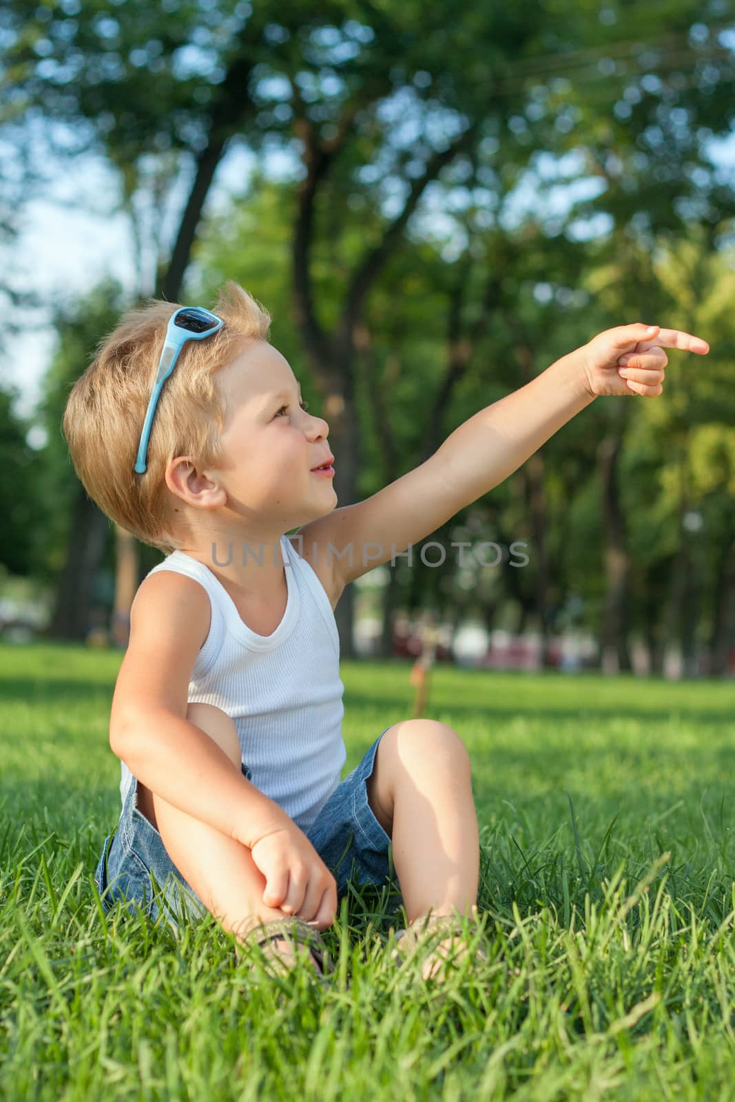 Little boy sitting in the park on a grass