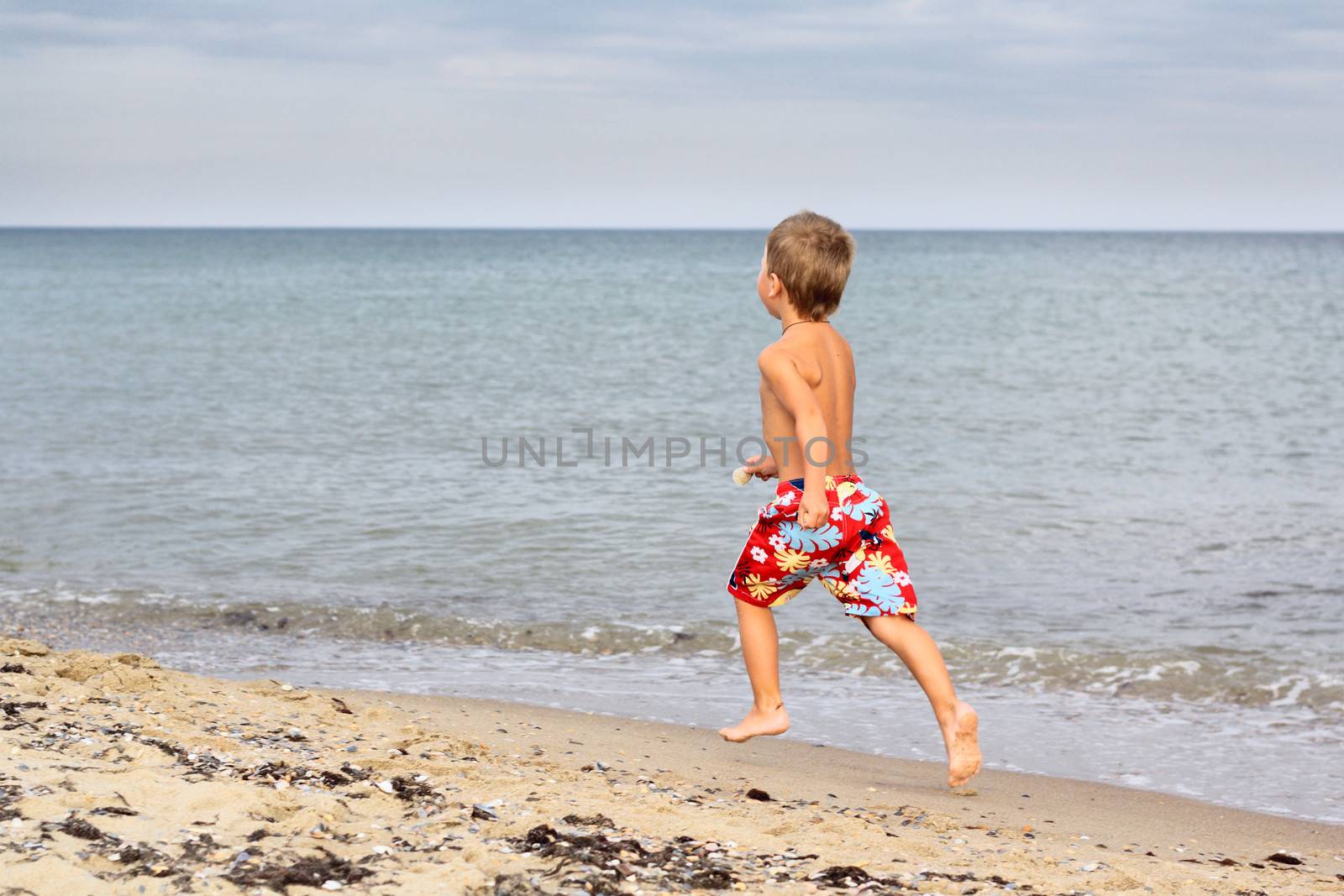 Little boy running at the seashore by dedmorozz