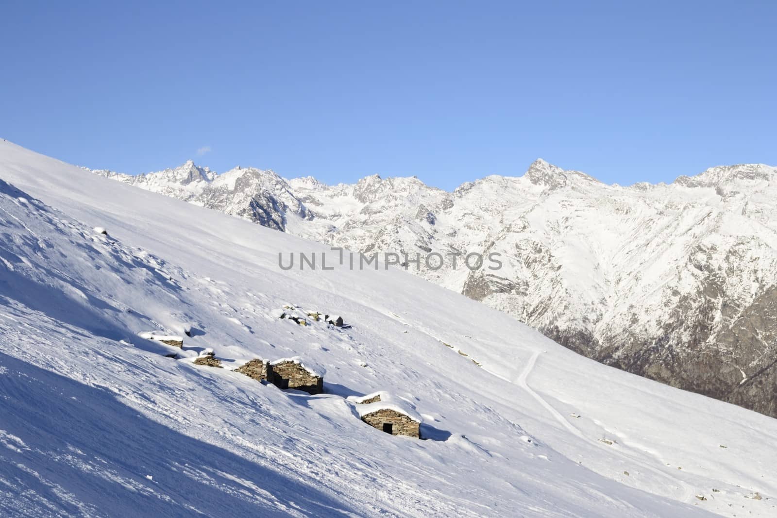 Old pasture huts in scenic winter background by fbxx