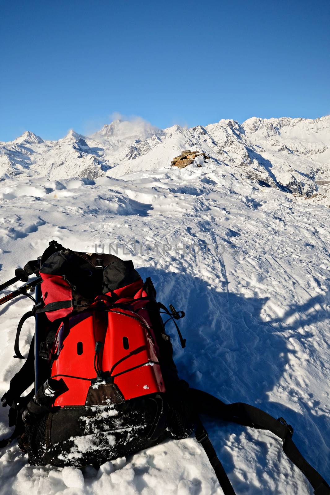 On the top of the mountain, pair of back country - tour ski and a backpack with avalanche safety tools. Scenic high mountain background (Gran Paradiso peak, 4061 m).