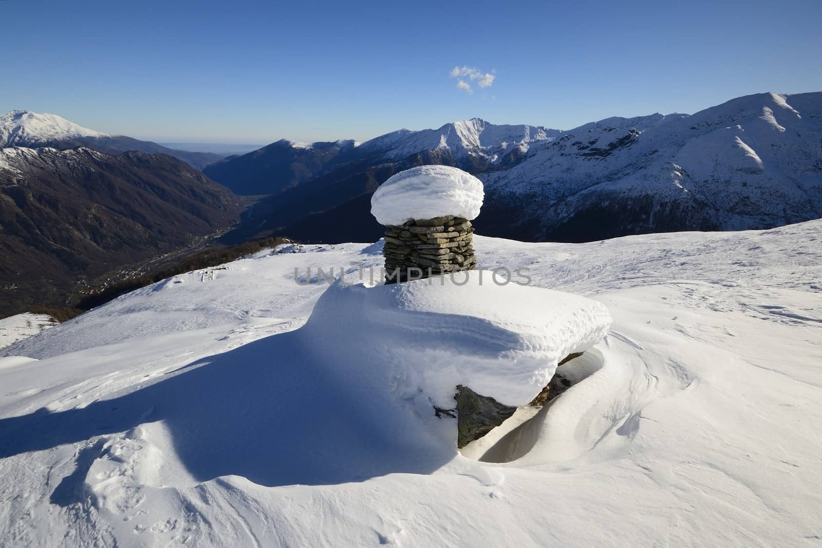 Winter landscape in the italian Alps with abandoned old alpine pasture huts, rocky boulders and smooth slopes covered by backcountry ski tracks.