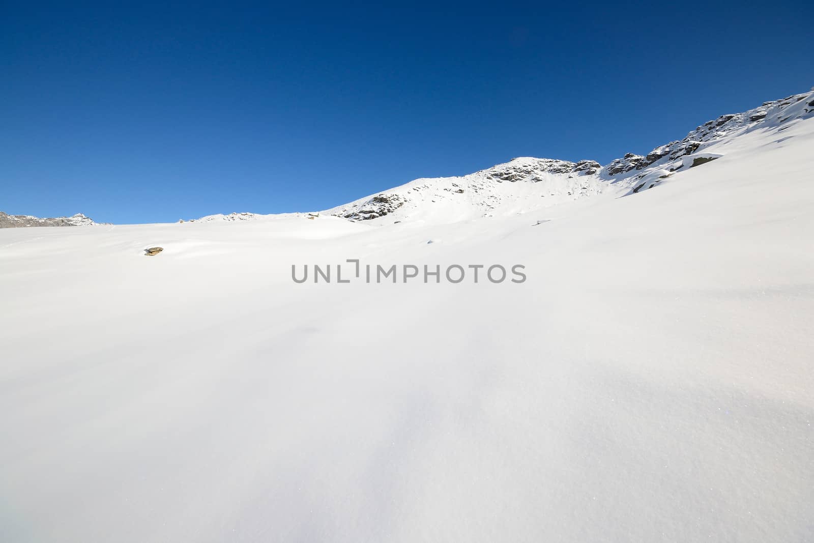 Candid off piste ski slope in scenic background of high mountain peaks, Gran Paradiso National Park, italian Alps