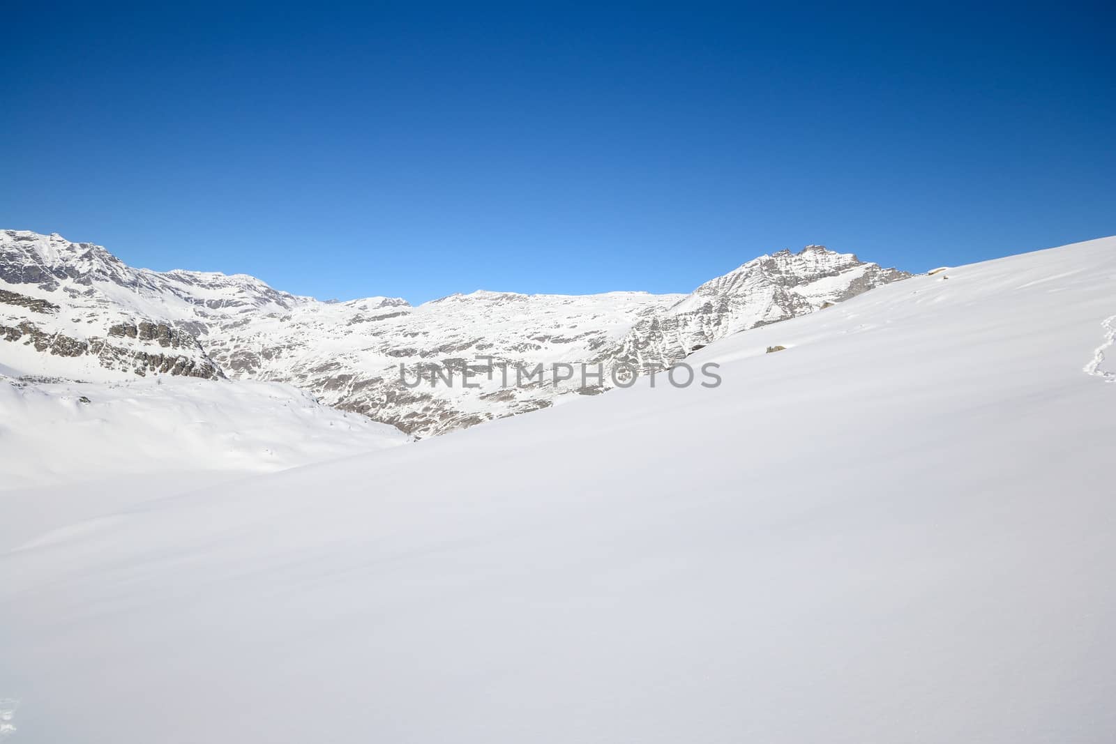 Candid off piste ski slope in scenic background of high mountain peaks, Gran Paradiso National Park, italian Alps