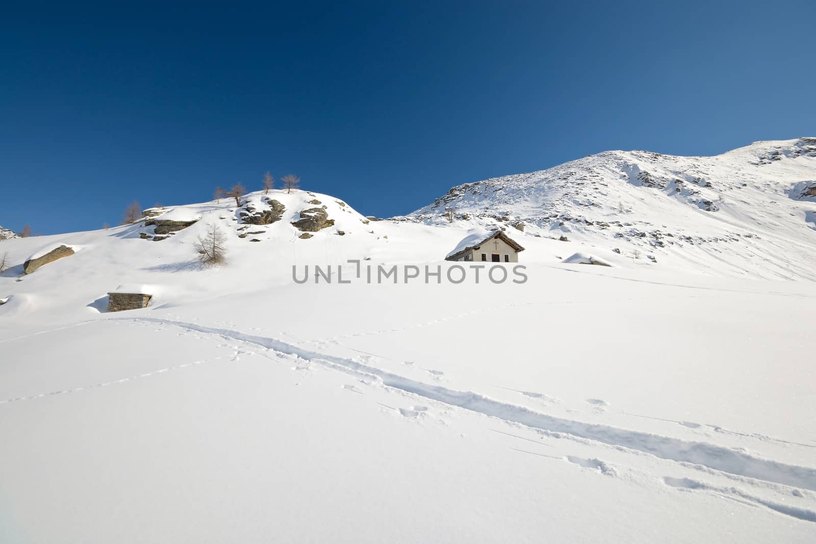 Little chapel high in the mountains with powder snow and back country ski tracks near Gran Paradiso National Park