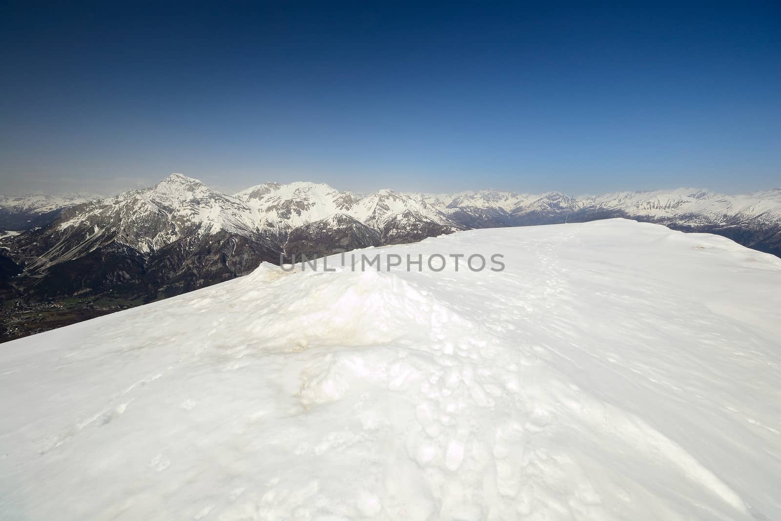 Ski resort and snowy slope in scenic background of high mountain peak