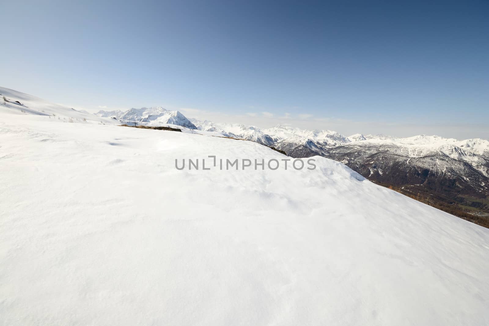 Ski resort and snowy slope in scenic background of high mountain peak