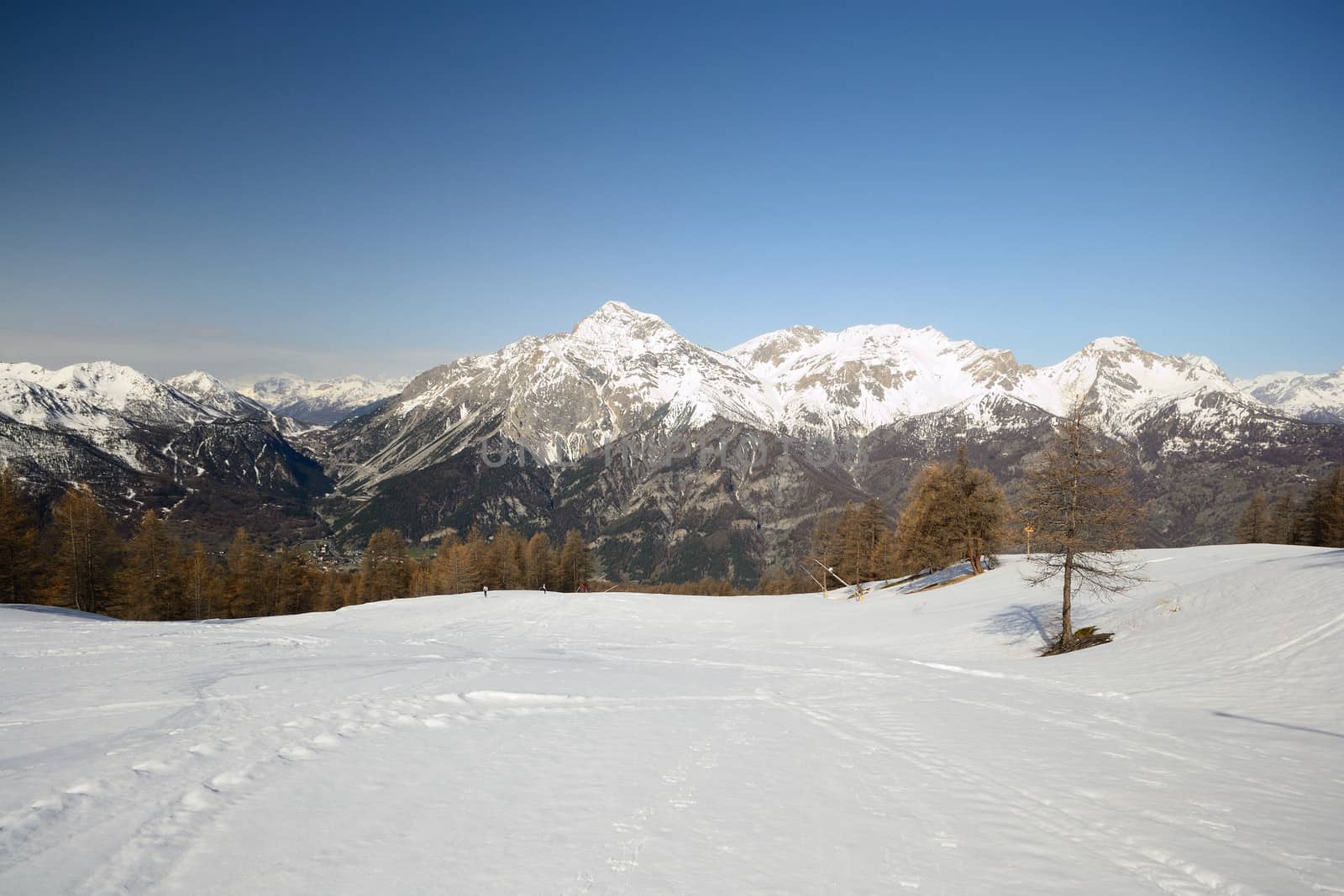 Ski resort and snowy slope in scenic background of high mountain peak