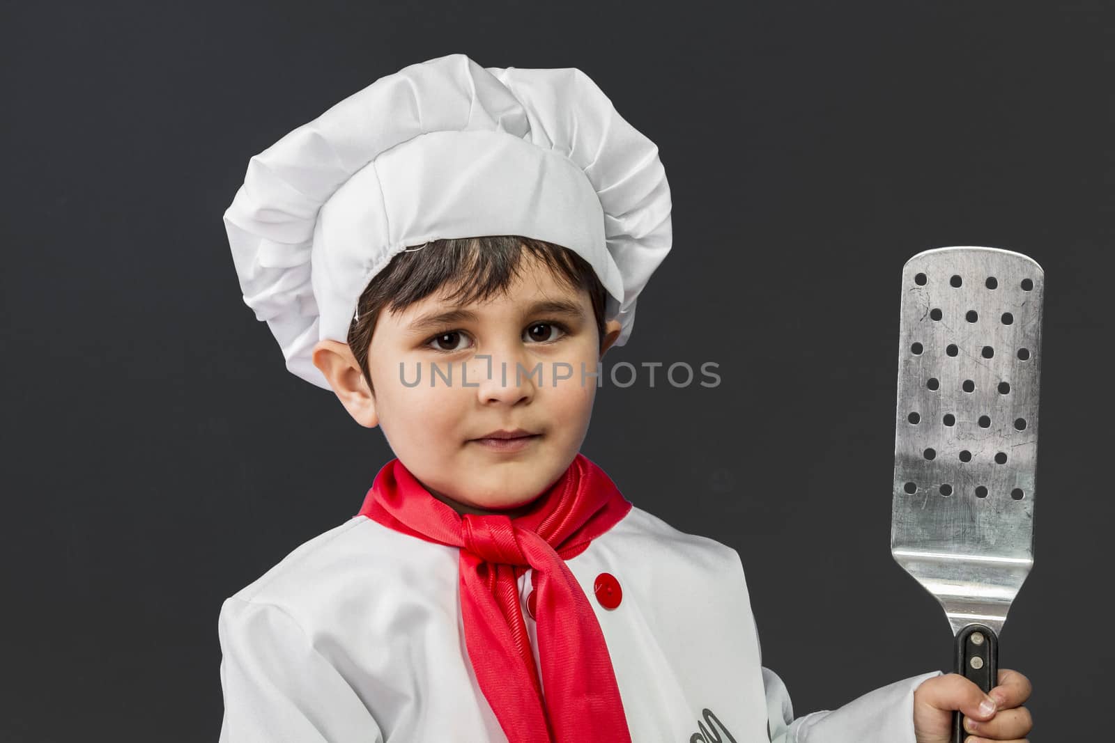 Childhood, Little boy preparing healthy food on kitchen over grey background, cook hat