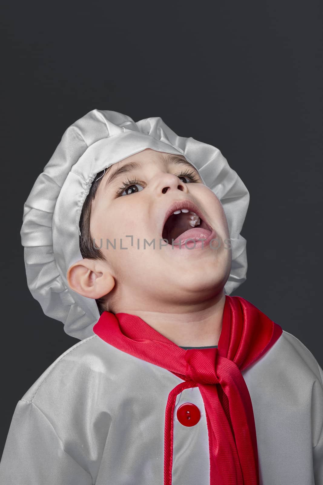 Fresh, little boy preparing healthy food on kitchen over grey background, cook hat