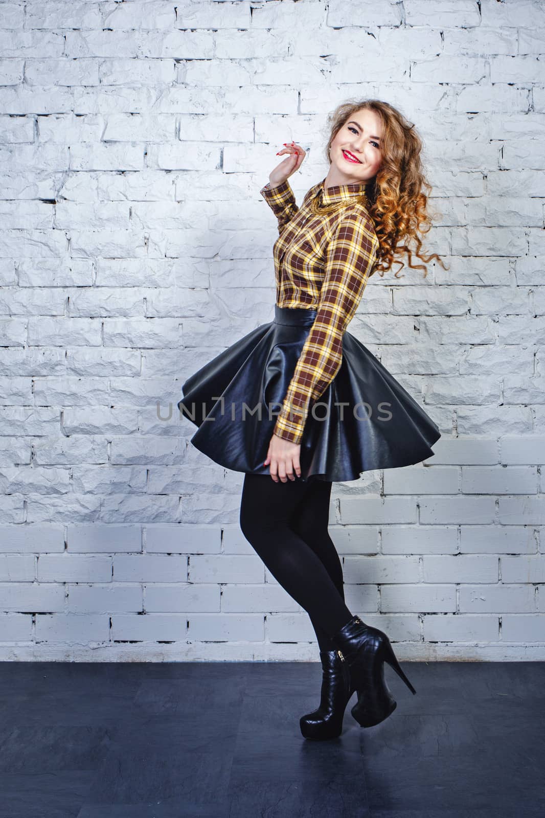 Attractive young girl in plaid shirt and leather skirt