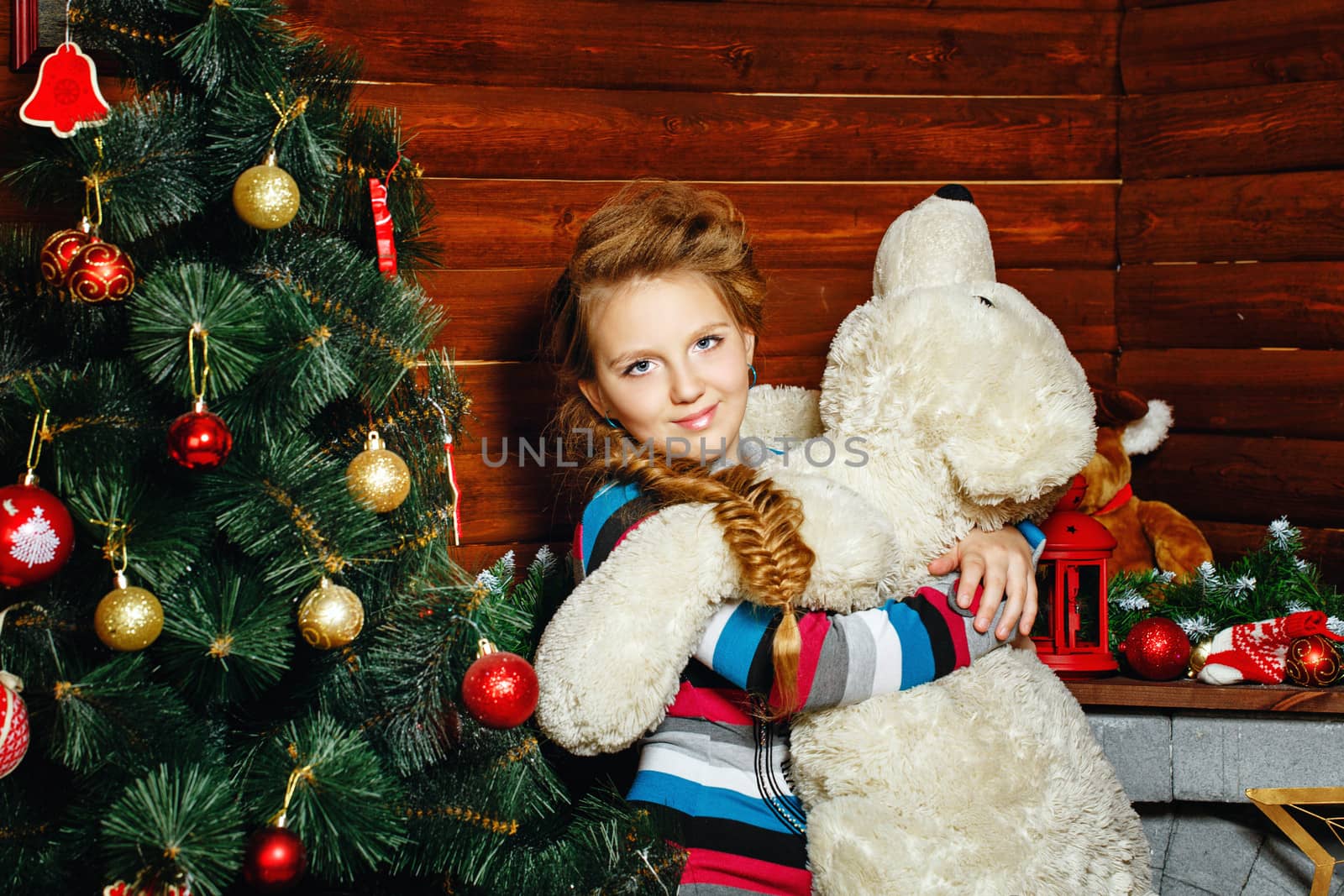 Little girl holding in her hands teddy bear near Christmas tree