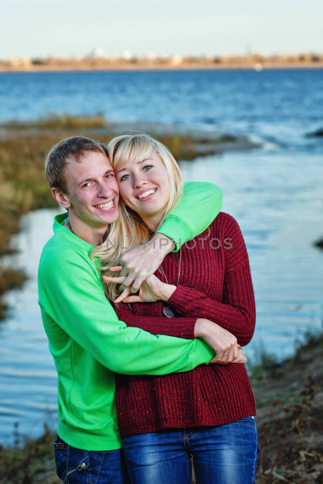 Young couple tenderly and lovingly embrace each other on banks of river