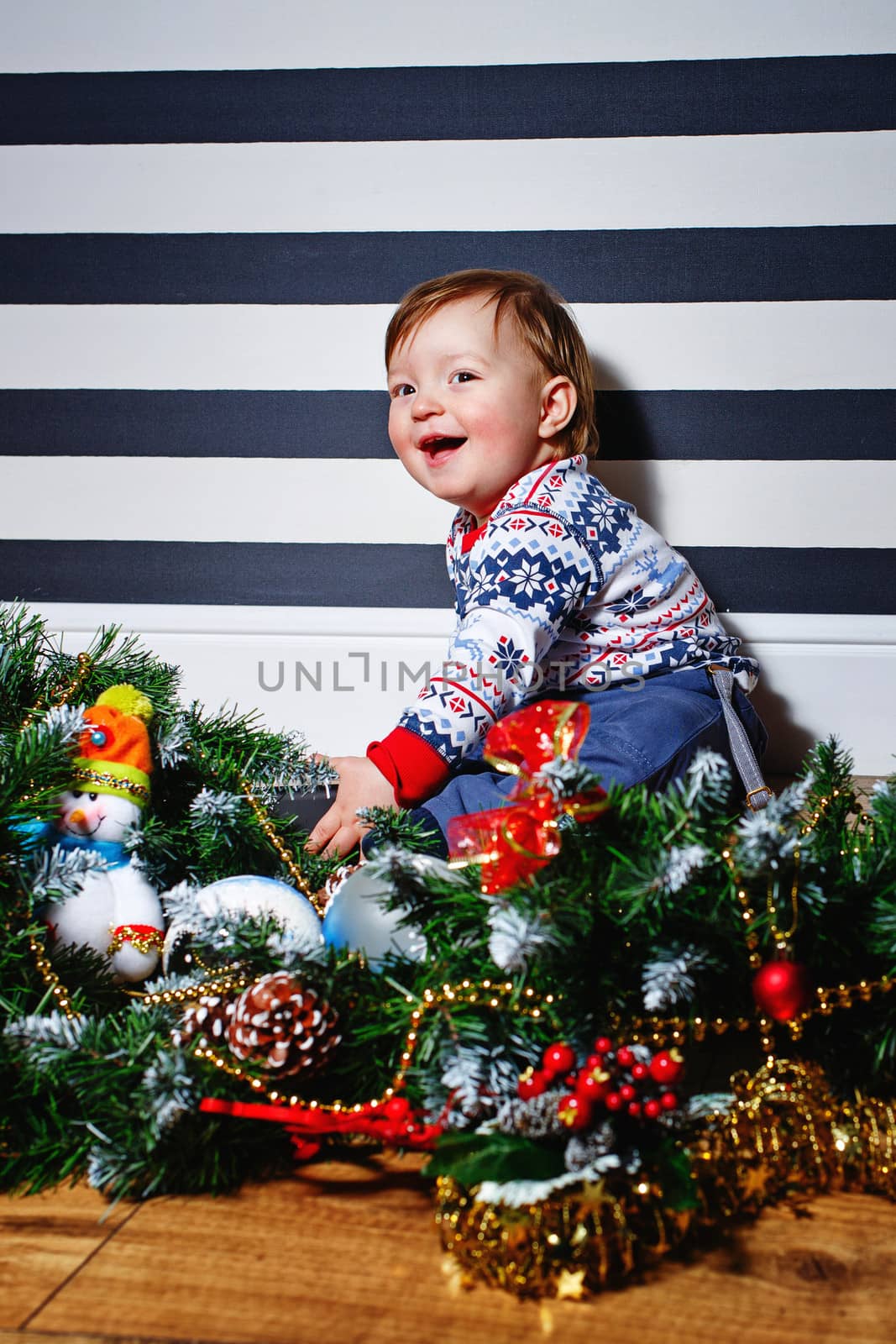 Little boy sitting on the floor surrounded by Christmas decorations