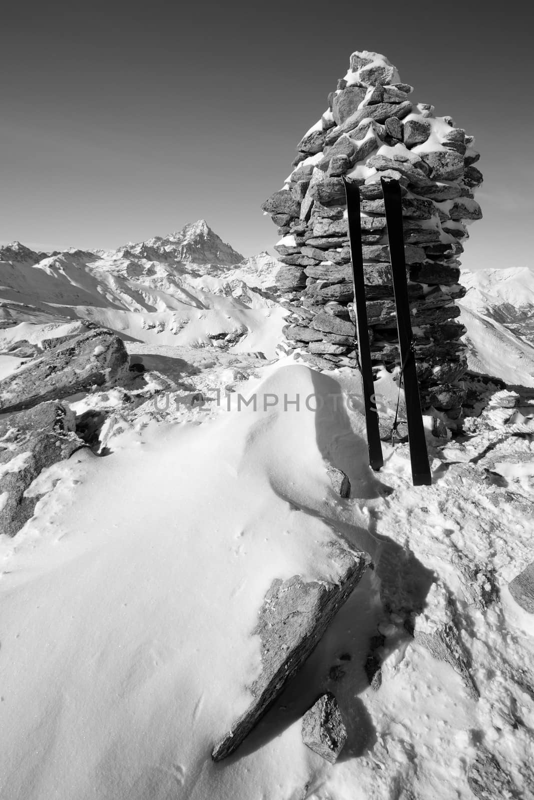 Pair of back country ski on the summit cairn with superb view of the italian alpine arc