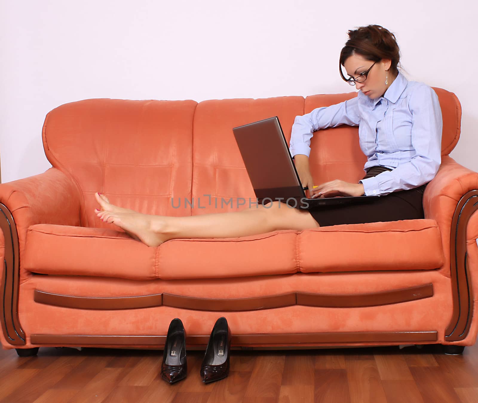 portrait of beautiful brunette sitting on a couch in the living room with lap top