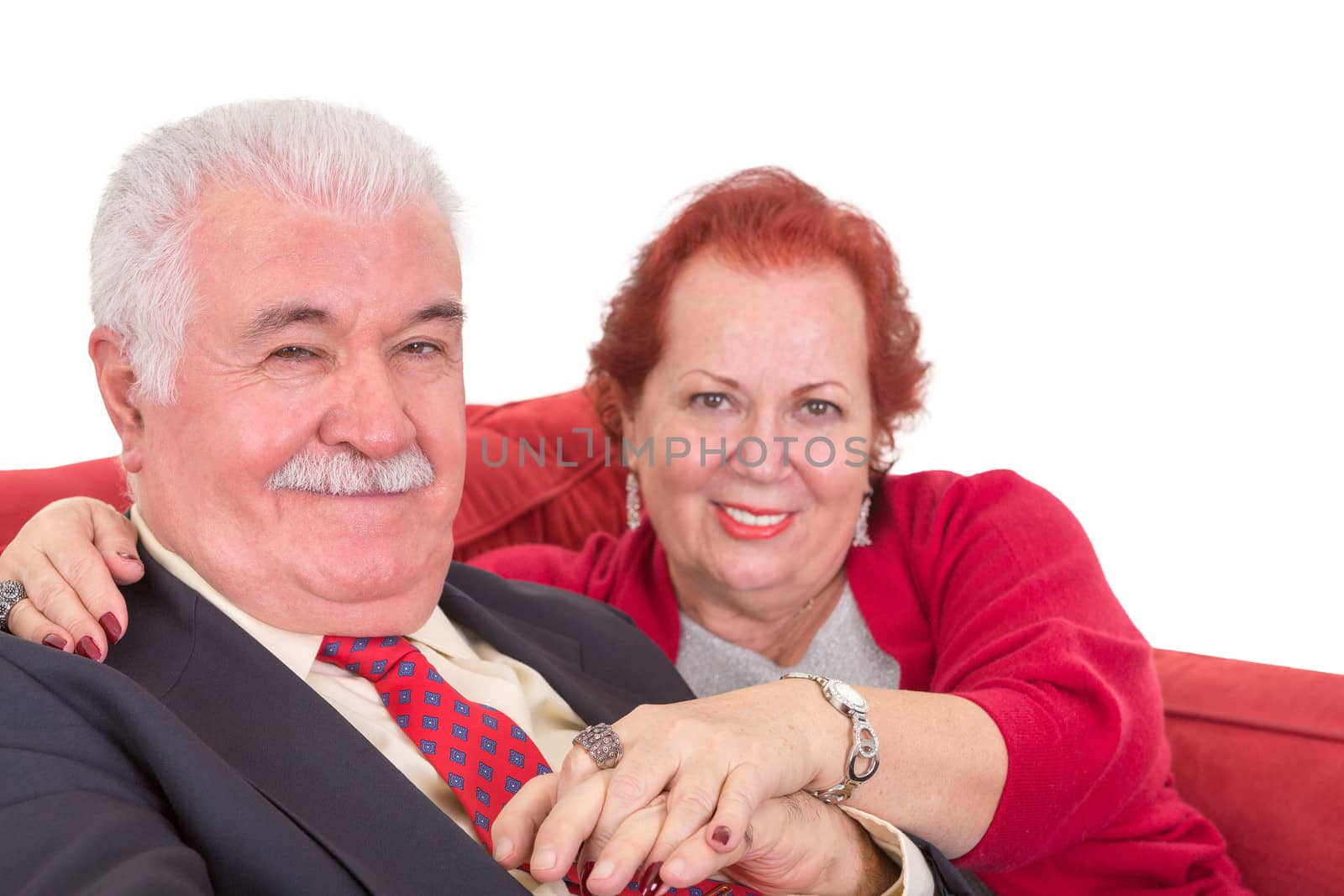 Affectionate senior couple on a red sofa by coskun
