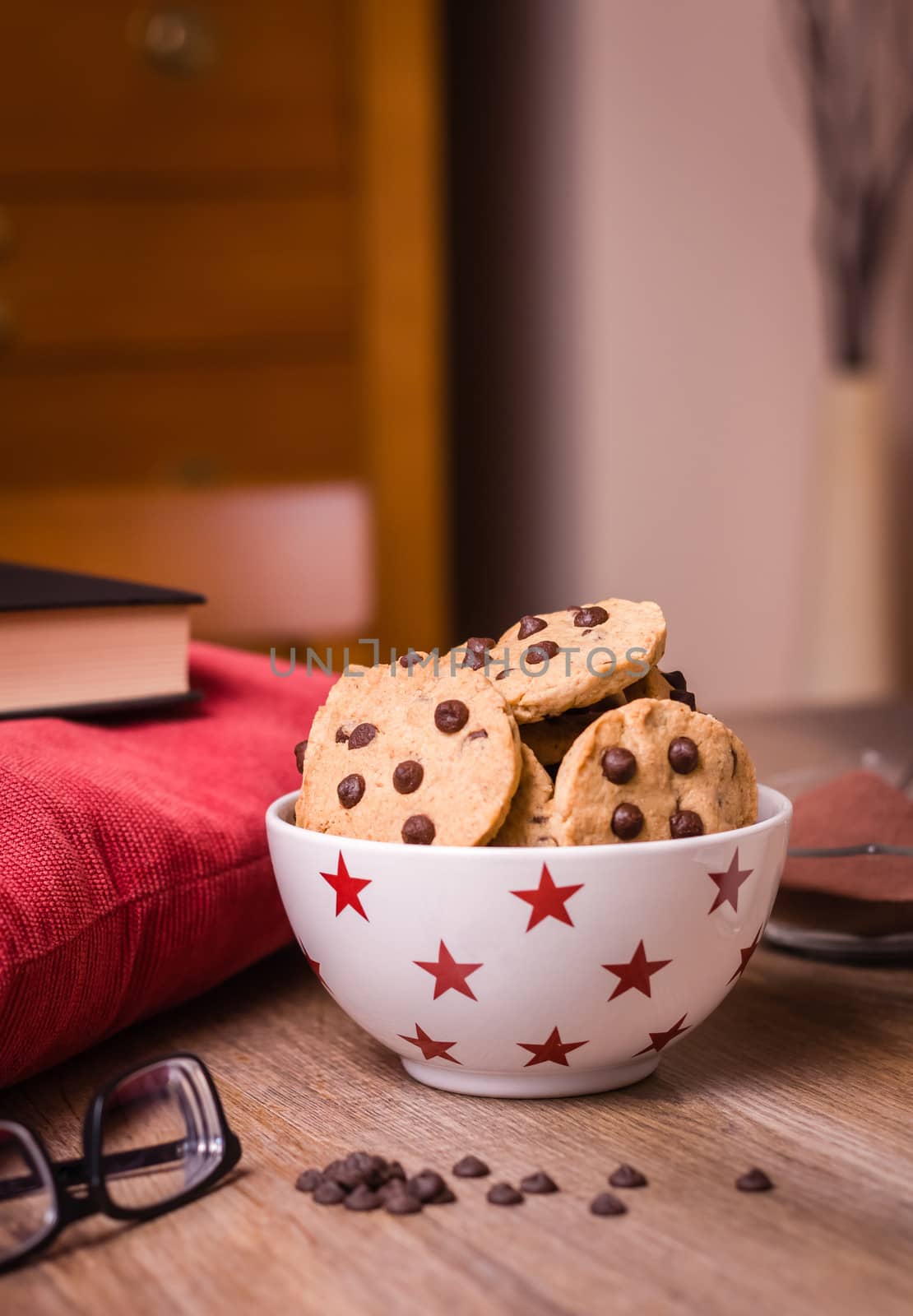 Closeup of chocolate chip cookies on stars bowl and milk glass over a wooden background