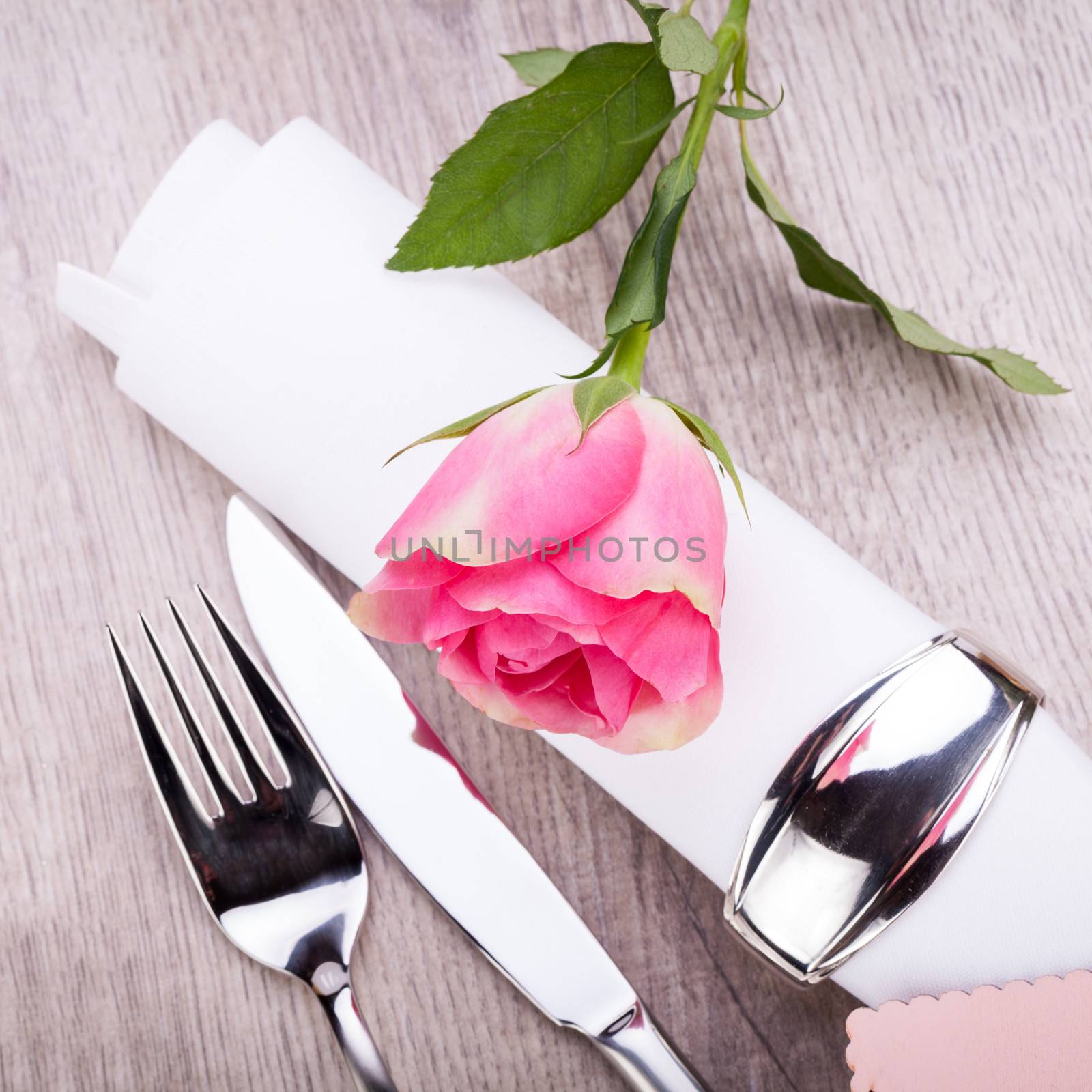 Romantic formal elegant table setting with a single pink rose and decorative ribbon for a sweetheart on Valentines Day