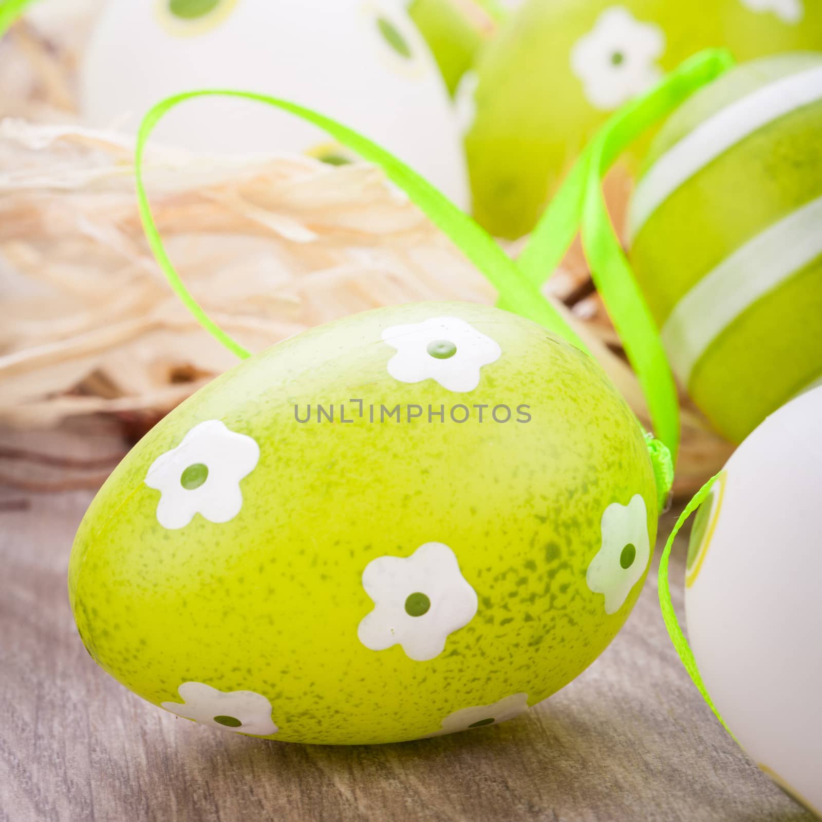 Collection of four hand decorated colourful green Easter eggs with different patterns displayed in straw, close up view