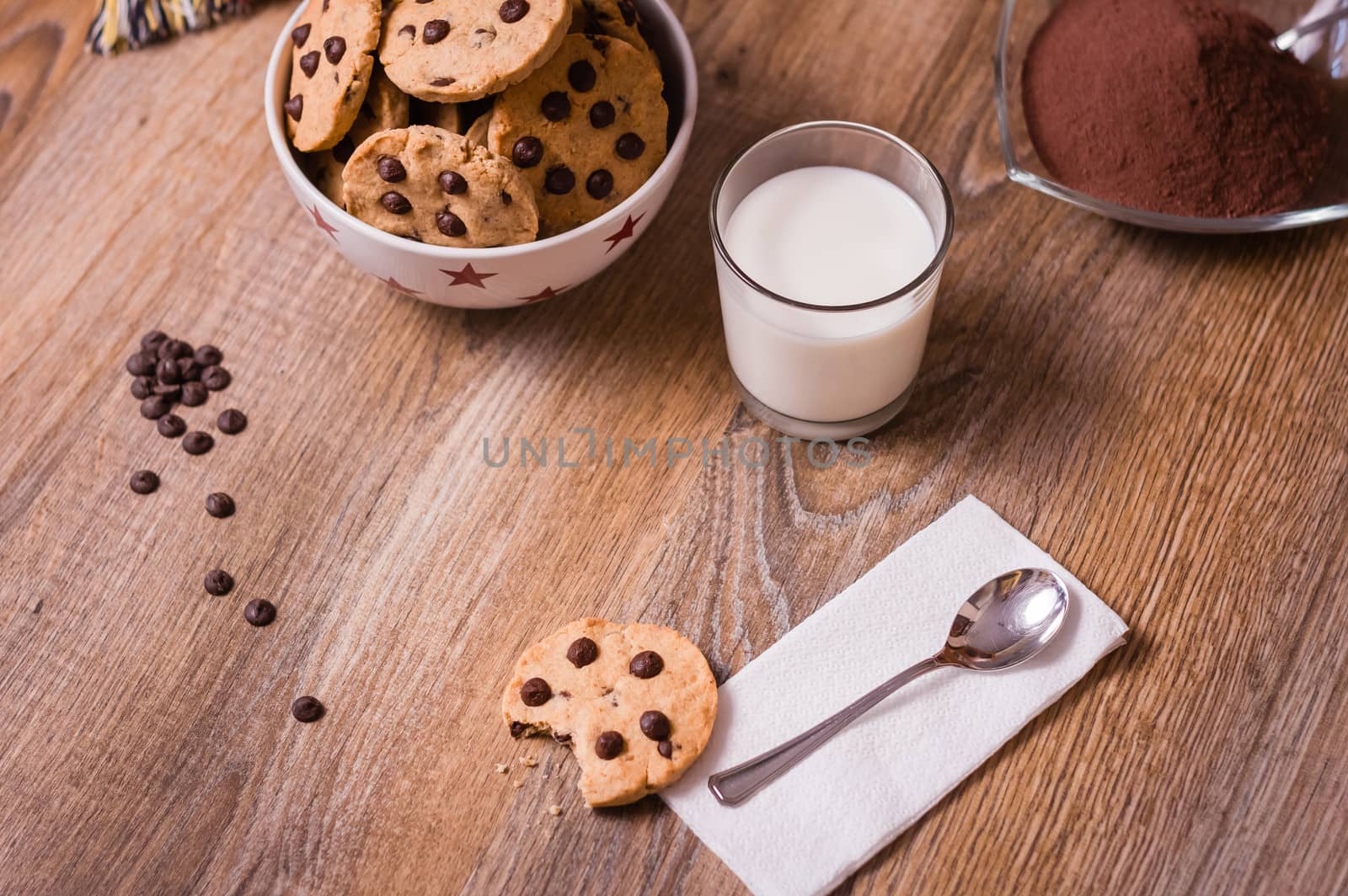 Closeup of chocolate chip cookies on stars bowl and milk glass over a wooden background