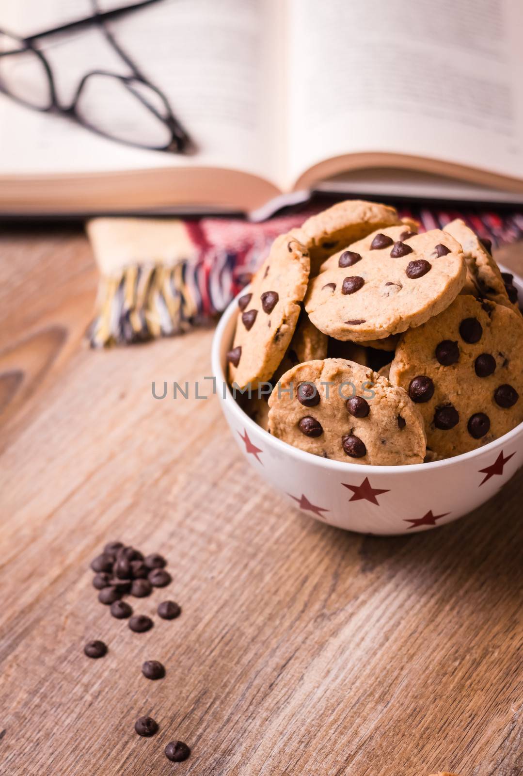 Closeup of chocolate chip cookies on stars bowl and book over a wooden background