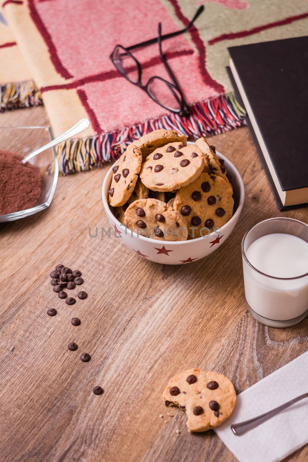 Closeup of chocolate chip cookies on stars bowl and milk glass over a wooden background