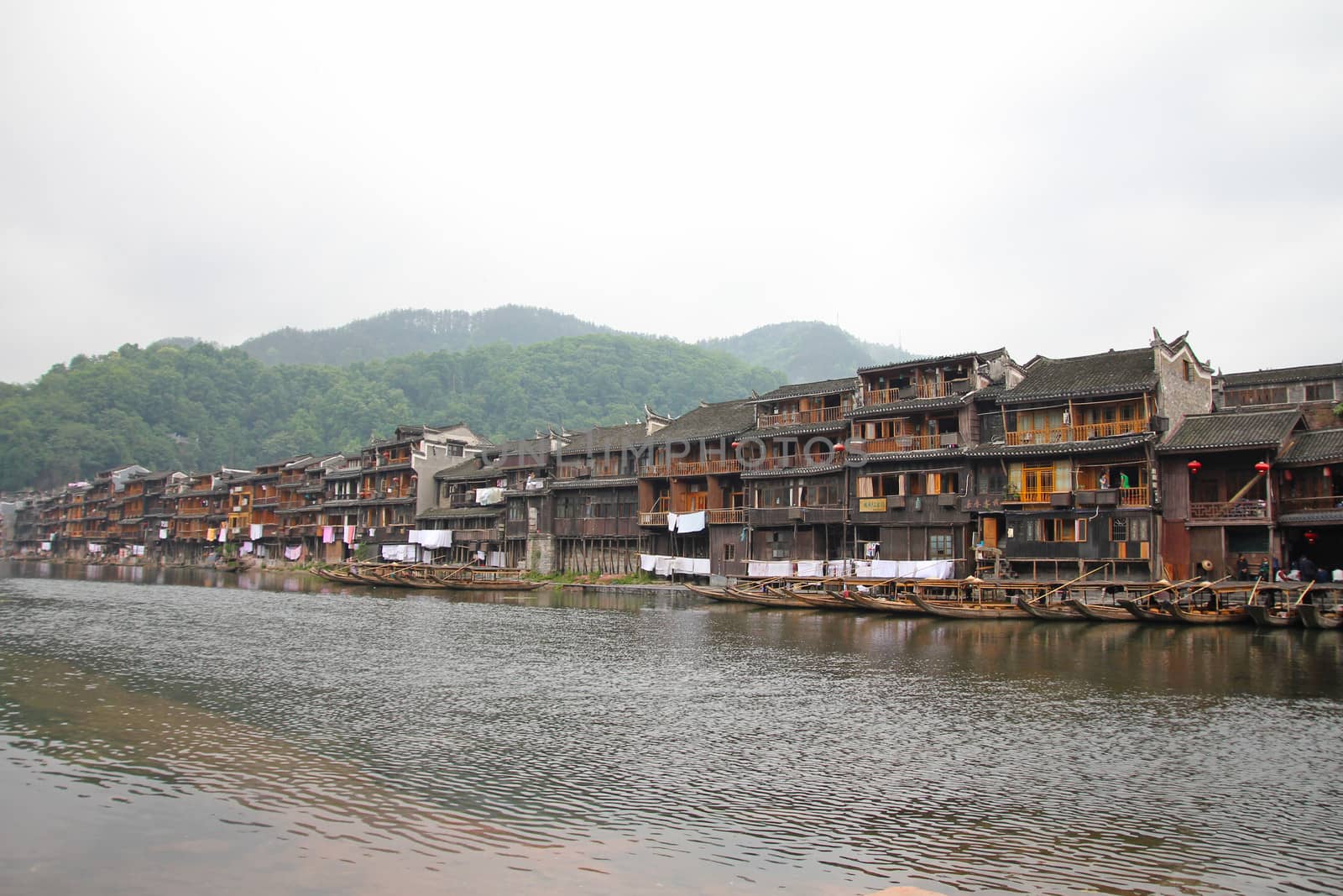 FENGHUANG - MAY 12: Wooden boat and wooden houses at tuojiang river in fenghuang ancient town on May 12, 2011 in Fenghuang, China.