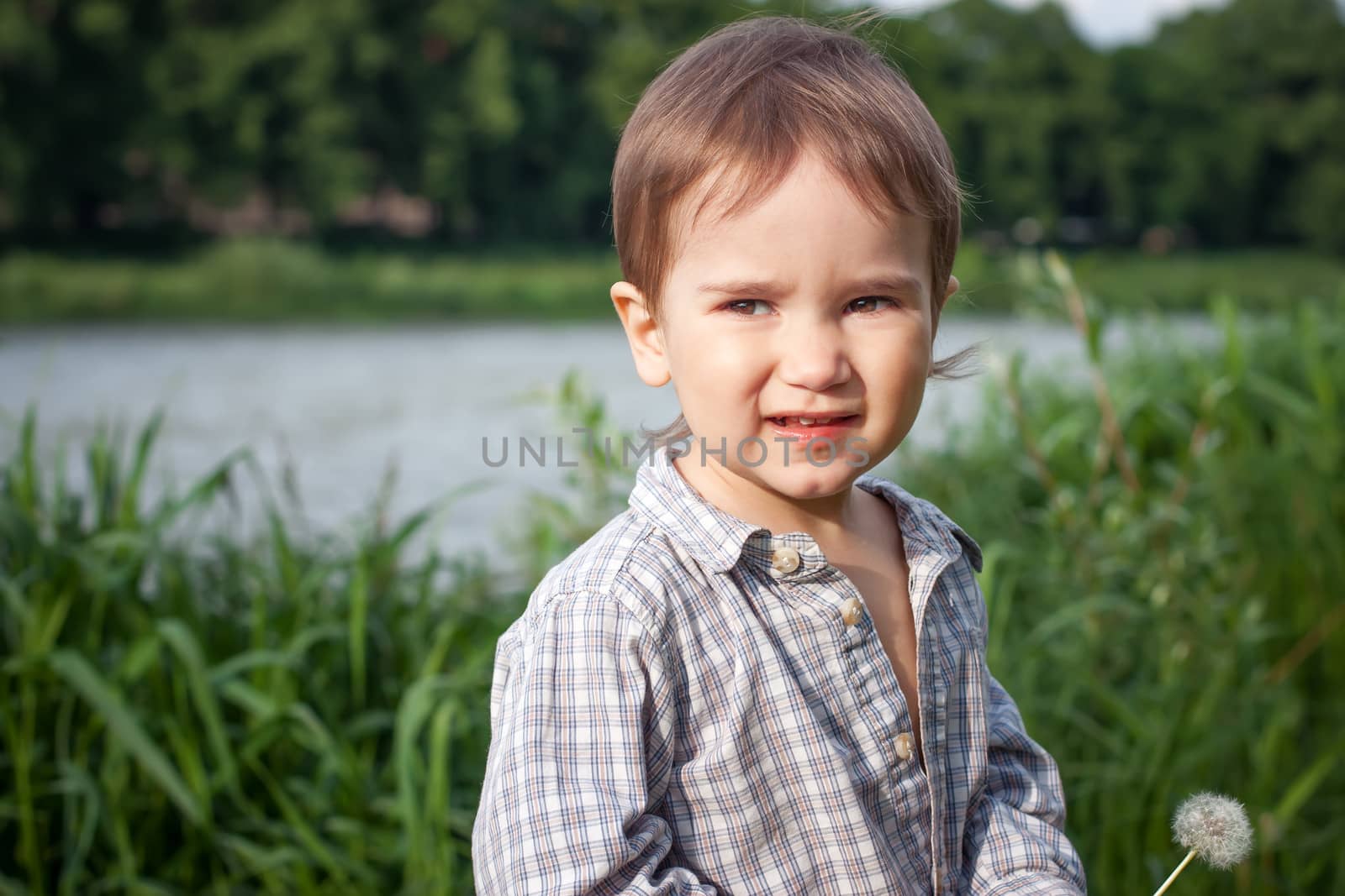 Child with dandelion outdoor near a river