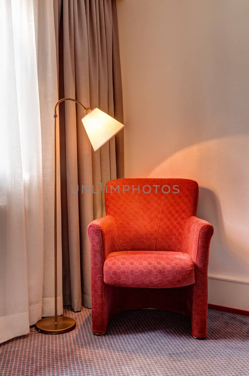 Red armchair and floor lamp in the corner of the room.