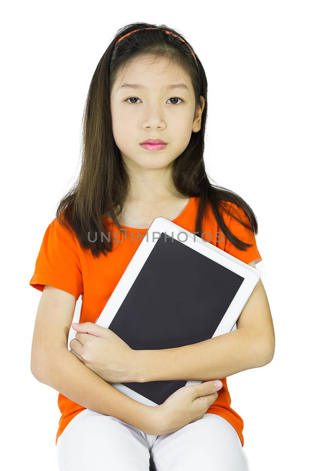 Asian young girl is holding tablet while sitting at table, isolated over white