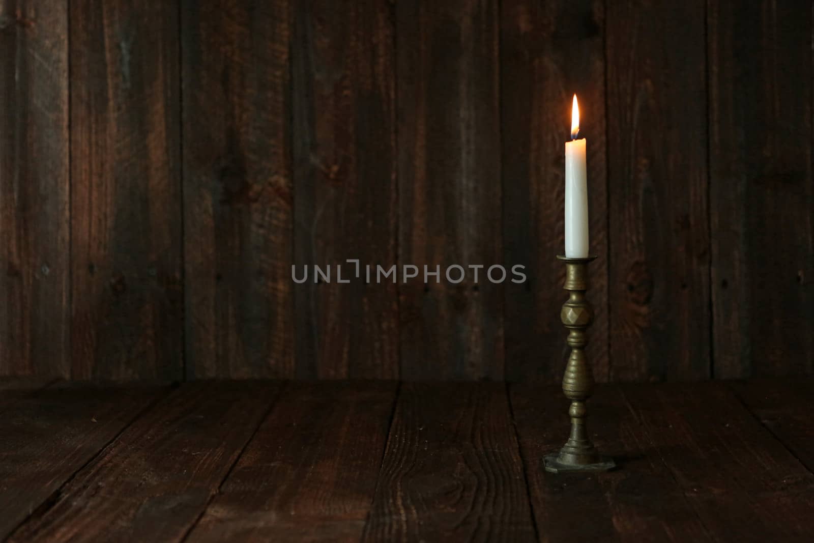 Lit Candle on an Old Wooden Rustic Background by tobkatrina