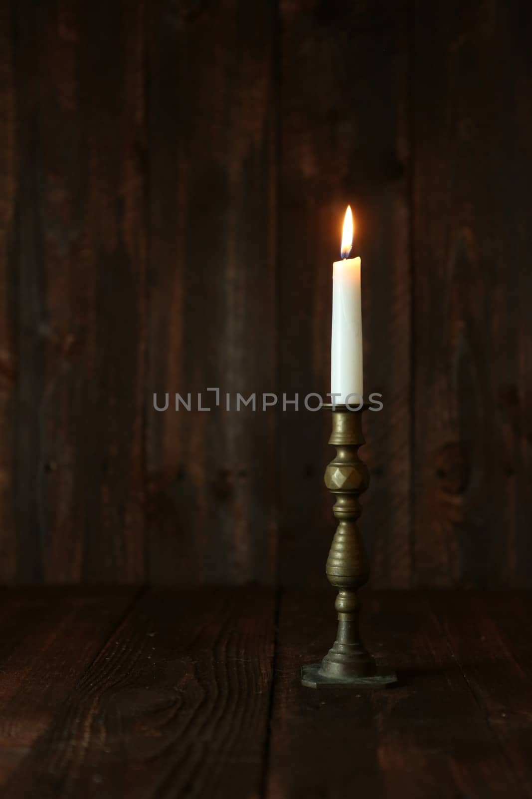 Lit Candle on an Old Wooden Rustic Background by tobkatrina