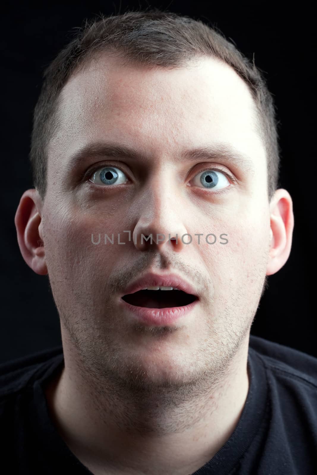 A shocked or surprised middle aged man over a dark background.