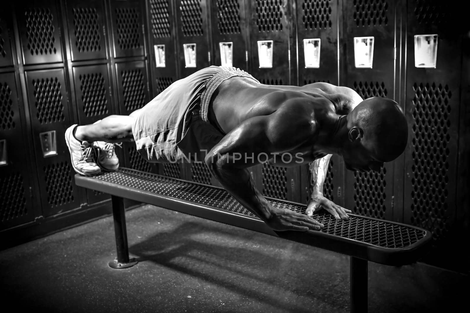 Portrait of a lean toned and ripped muscle fitness man under dramatic low key lighting in black and white.