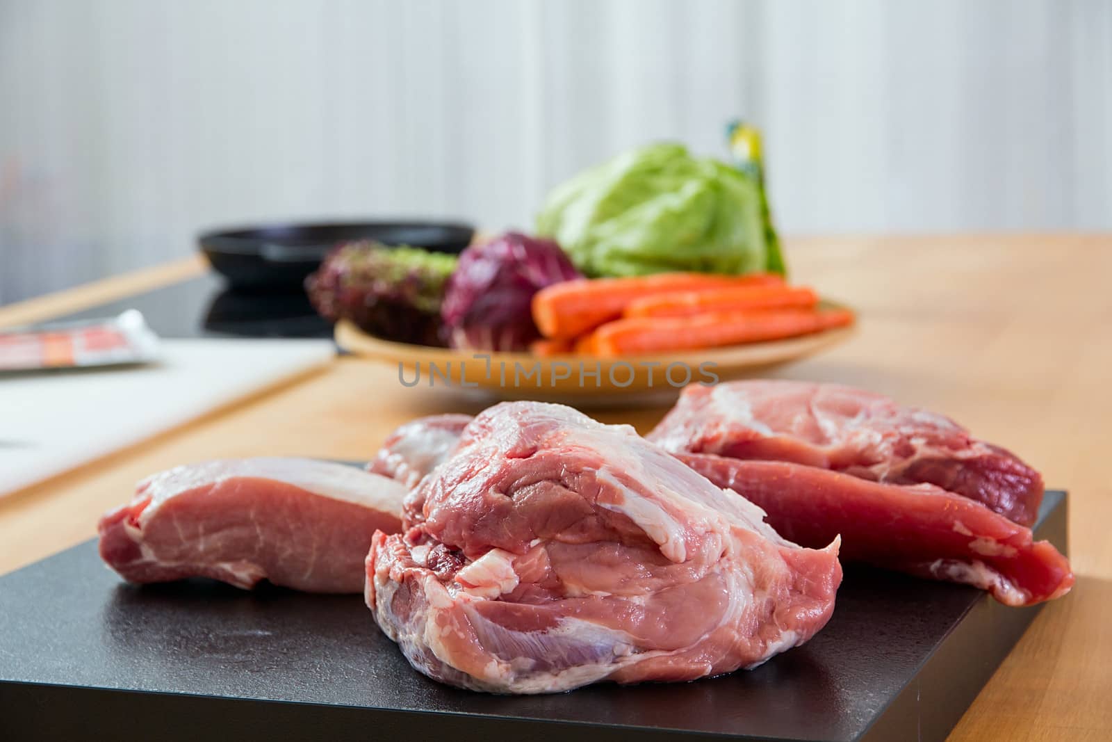 Meat parts on the table with vegetables at background