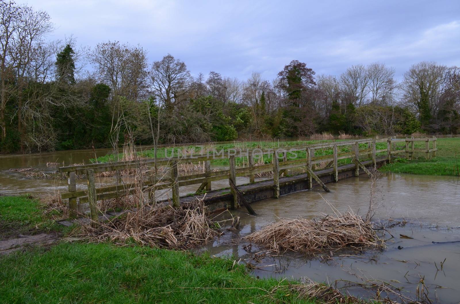 A rustic wooden footbridge crossing a swollen river.