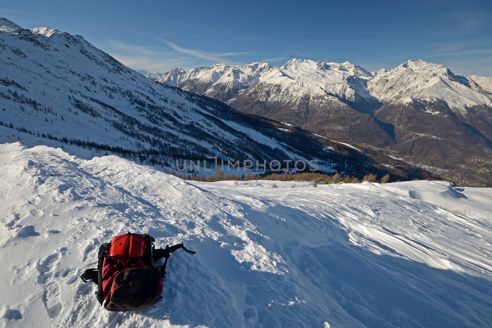 Backpack with avalanche safety tools (a red part of shovel in the foreground) in a scenic high mountain background