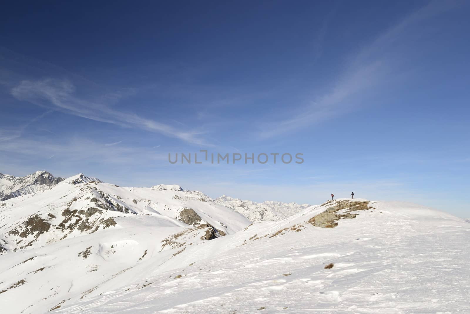 Candid off-piste ski slope in scenic background of mountain peaks, valleys and plain. Piedmont, Italian Alps